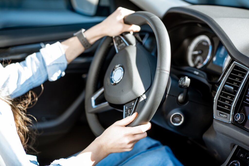 Woman in the driver's seat of a car holding the steering wheel